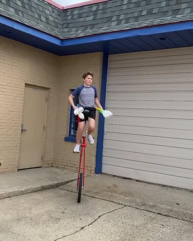 Boy Does Juggling With Five Pins While Riding Giraffe Unicycle