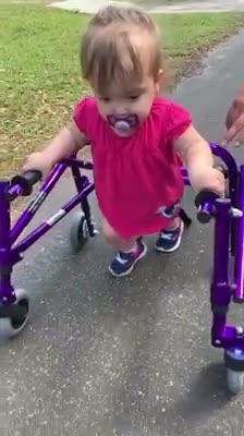 Toddler Battling From Spina Bifida Practices Walking With Supporter