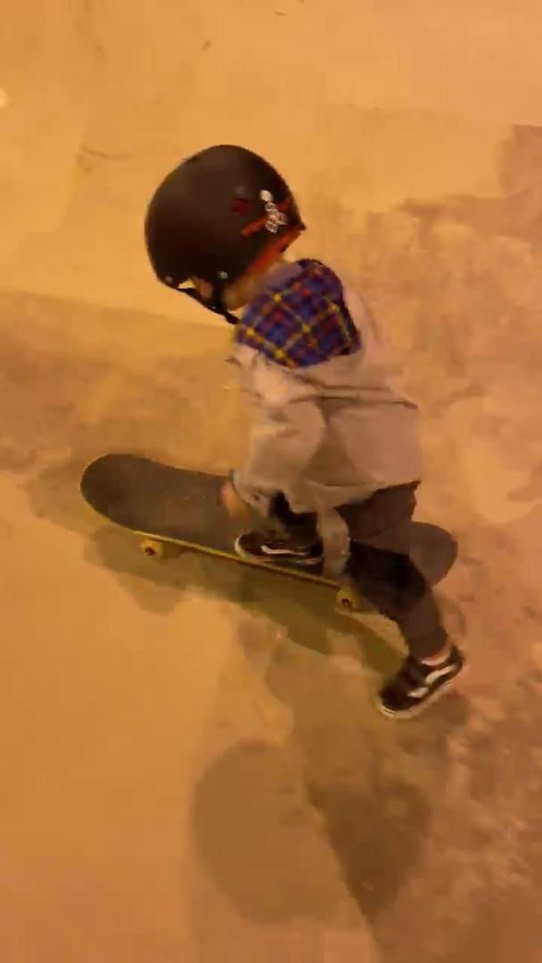 Toddler Puts Both Feet up on Skateboard and Rides Around